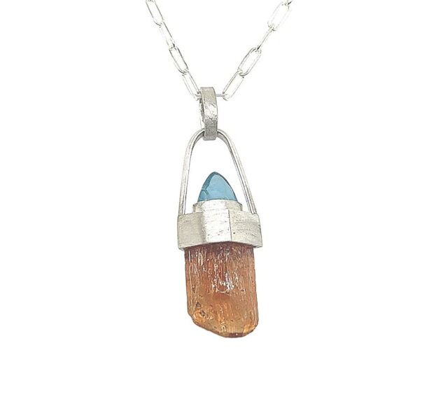 Imperial Topaz Crystal and Blue Apatite Pendant. Classic peachy pink Imperial Topaz with natural crystal faces in a sterling silver pendant. 18” sterling silver chain and clasp included. 1 ½ h x ½ “w.